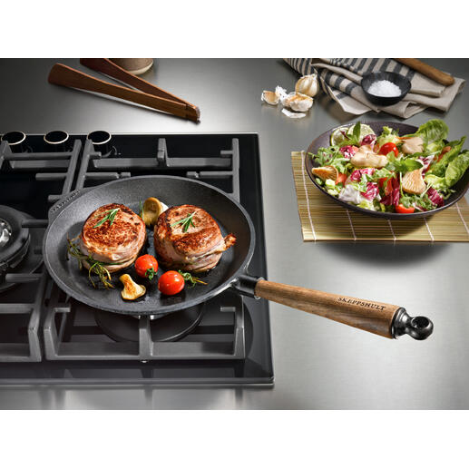 Gietijzeren pan op het fornuis met gebakken vlees en groenten