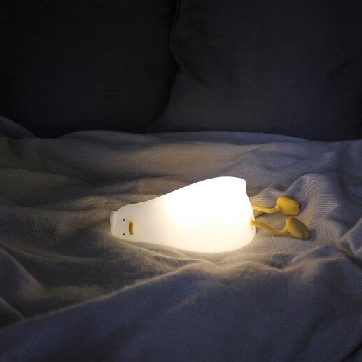 Moedige eend nachtlampje gloeit op een bed.