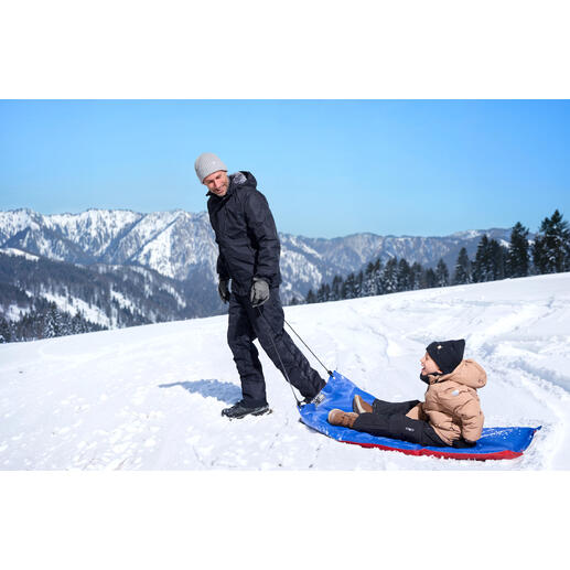 Man trekt XL-sneeuwslee met een kind over een besneeuwd landschap.