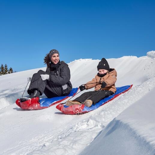 Vrouw en kind glijden van een sneeuwhelling met XL-sleetjes.