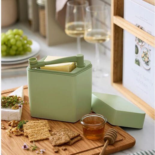 Kaas vershoudbox met snijder op een houten snijplank naast crackers en honing.