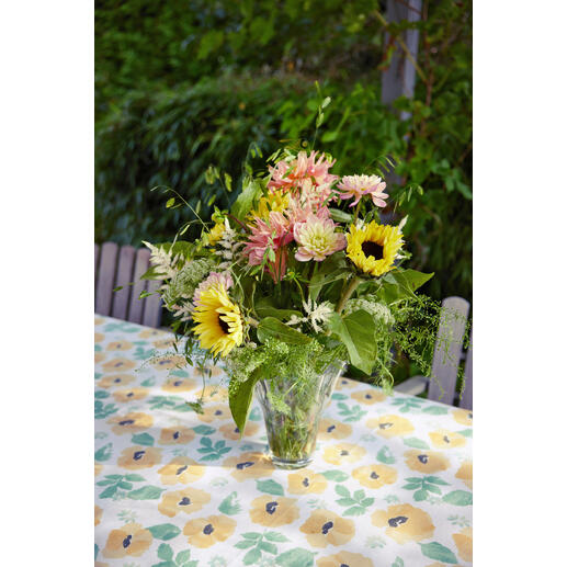 Tafel gedekt met aquarelle tafelkleed en boeket bloemen.