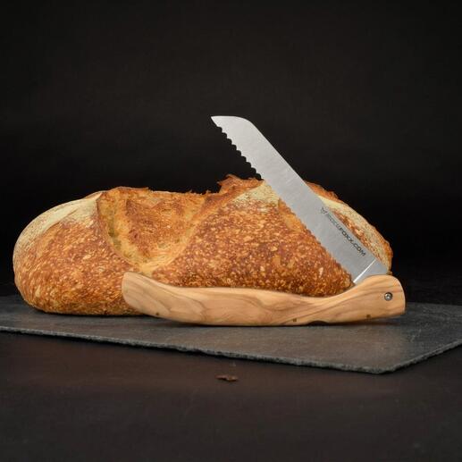 Opvouwbaar broodmes met olijfhouten handvat naast een brood op een zwarte ondergrond.