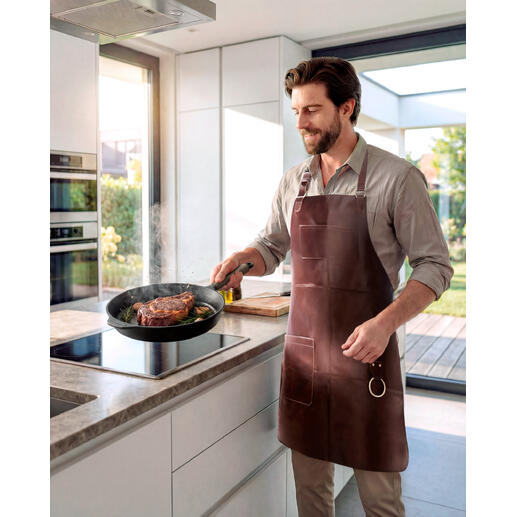 Man met een buffellederen schort kookt in een moderne keuken.