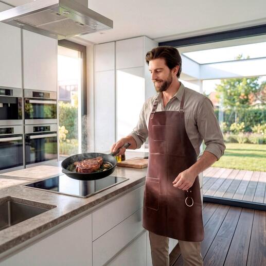 Man met een buffellederen schort kookt in een moderne keuken.