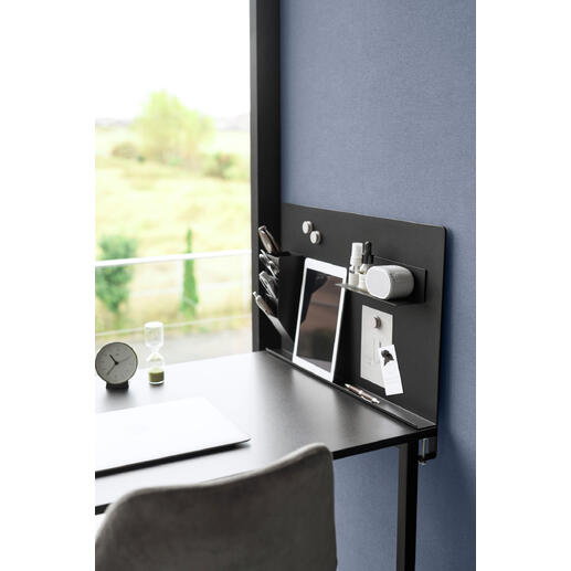 Zwarte magnetische prikbord met kantooraccessoires op een bureau.