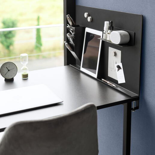 Zwarte magnetische prikbord met kantooraccessoires op een bureau.