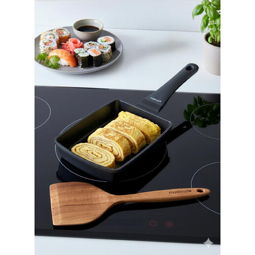 Tamagoyaki-pan met opgerolde eieren naast een sushi-schaal.