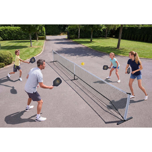Gezin speelt Pickleball buiten, met net en ballen.
