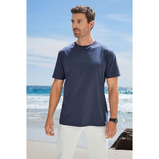 Man in een donkerblauw T-shirt staat op het strand met uitzicht op de camera.