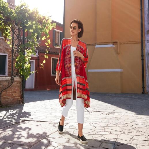 Vrouw in rood met IVKO kimono-vest, loopt op een geplaveide plaats