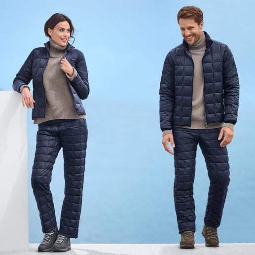 Man en vrouw in Taion donjack en -broek, beide in donkerblauw, voor een blauwe achtergrond.