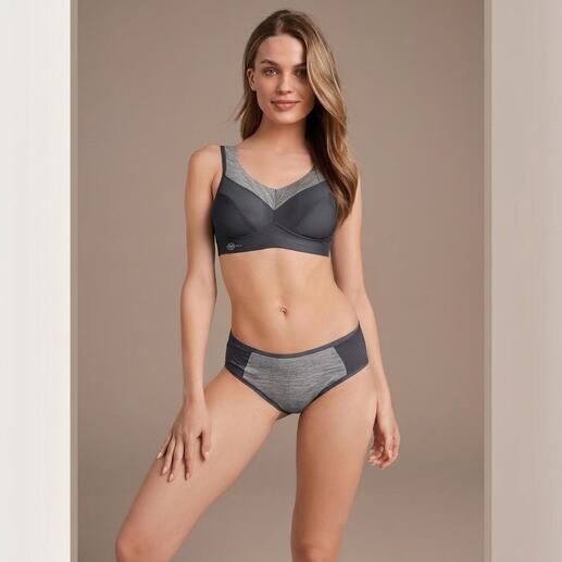 Vrouw in sportbh en panty in een donker ontwerp, glimlachend.