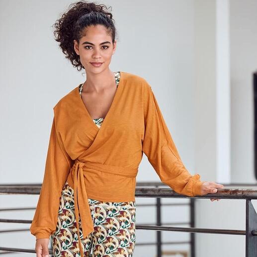 Vrouw in Mandala-outfit met wikkeljack en leggings, glimlachend.