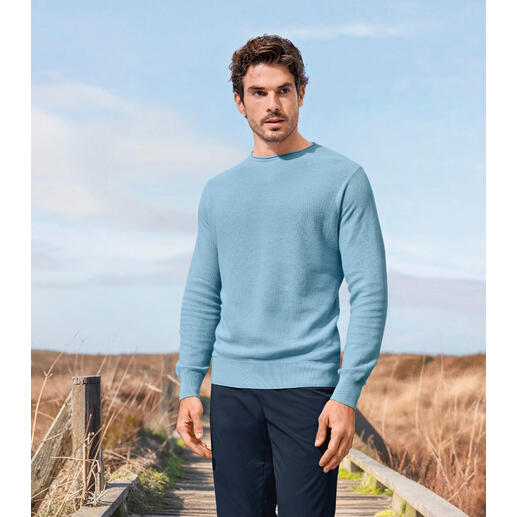Junghans 1954 stijlvolle piqué-trui Man in een lichtblauw edel piqué sweater staat in een landelijke omgeving.