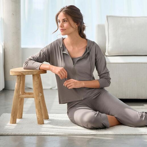 Vrouw zit in een elegante loungewear-combinatie op een tapijt.