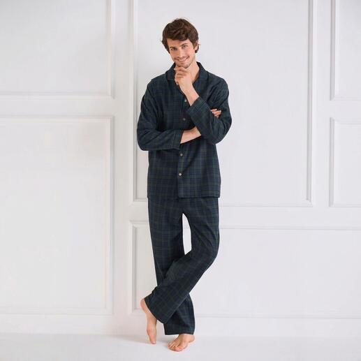 Man in een geruit flanellen pyjama, staat met gekruiste armen.