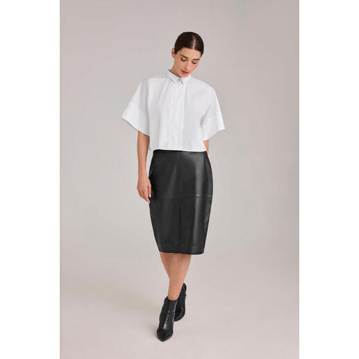 Witte boxy oversize blouse, gedragen door een vrouw met een zwarte rok.