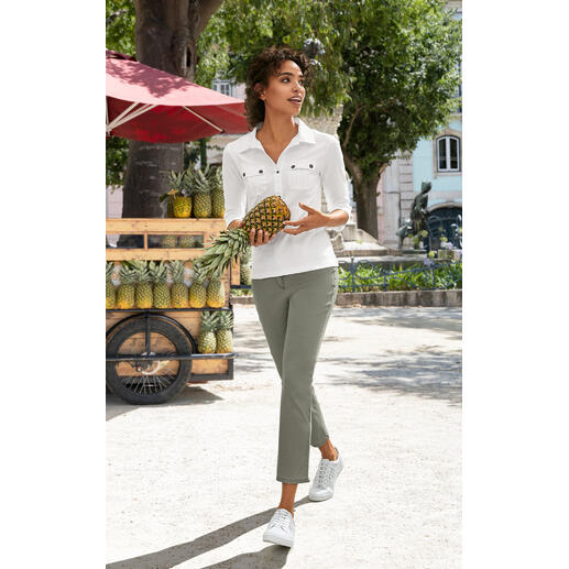 khaki Vrouw in witte blouse en groene broek houdt een ananas vast terwijl ze loopt.