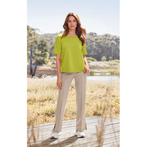 Vrouw in groene top en beige stoffen broek op het platteland.