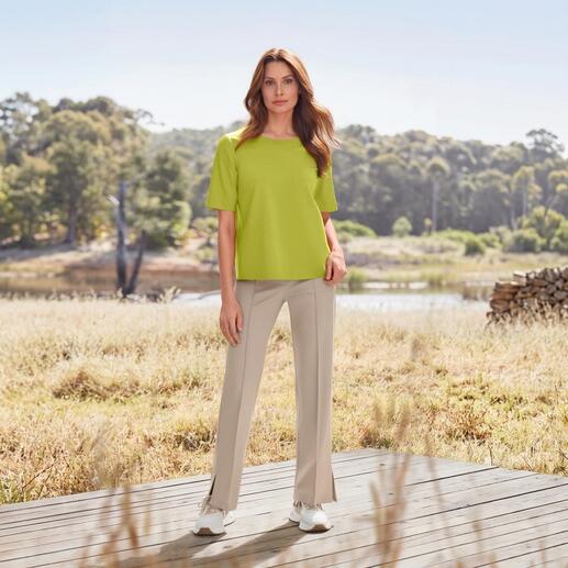 Vrouw in groene top en beige stoffen broek op het platteland.