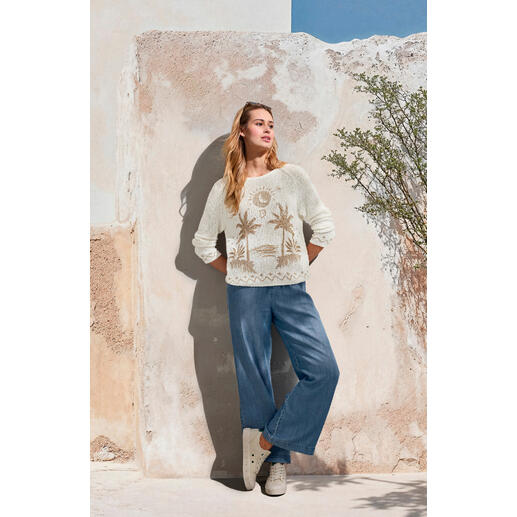 Bella Dahl jeans met wijde pijpen Vrouw in crème kleurige trui en lichtblauwe wijde jeans, voor een muur.