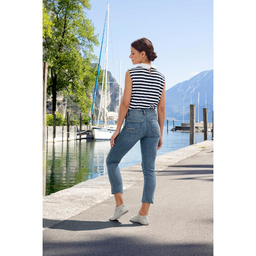 Silver Suki straight jeans Vrouw in gestreept top en jeans op een trottoir bij het water.