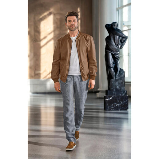 OCONI keerbare blouson van metisleer Man draagt een bruine OCONI Metis omkeerbare blouson, met een standbeeld op de achtergrond.