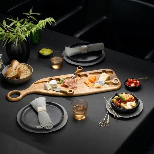 Design serveerplank van acaciahout met kaas, fruit en snacks op een donkere tafel.