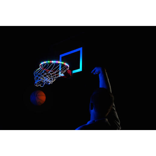 Basketbalnet met kleurrijke LED-lampen en persoon die gooit op een donkere plek.