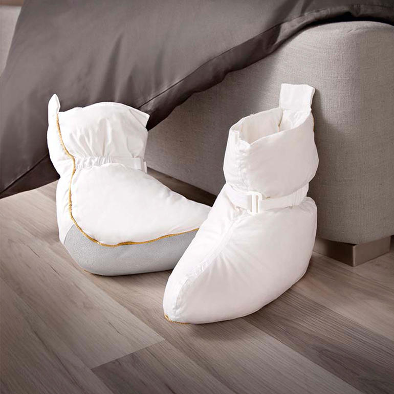 Schoenen voor in bed van zacht materiaal op een houten vloer.