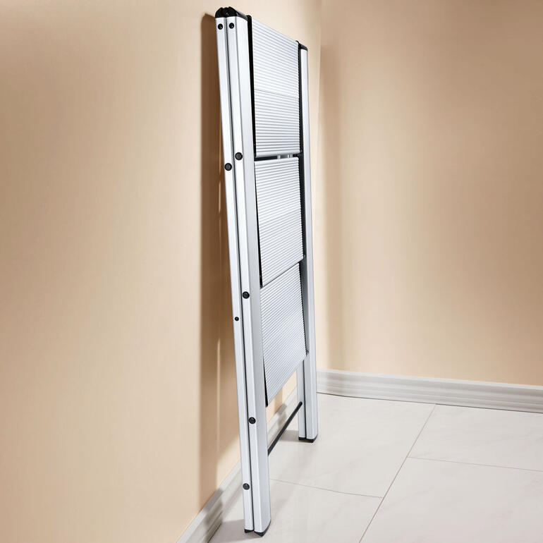 Geopende Italiaanse aluminium ladder staat tegen de muur.
