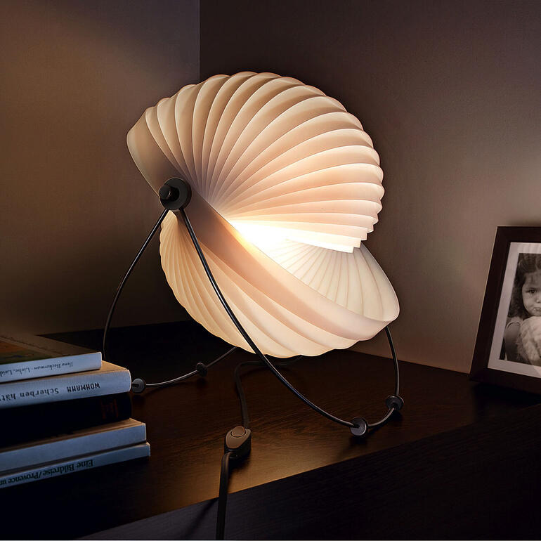Designlamp 'Eclipse' met een gebogen, bloembladvormige lamp op een tafel.