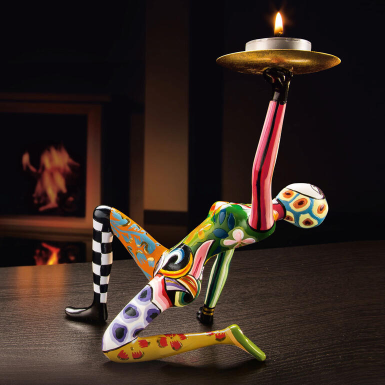 Kleurrijke sculptuur van Tom met een kaars op een tafel.
