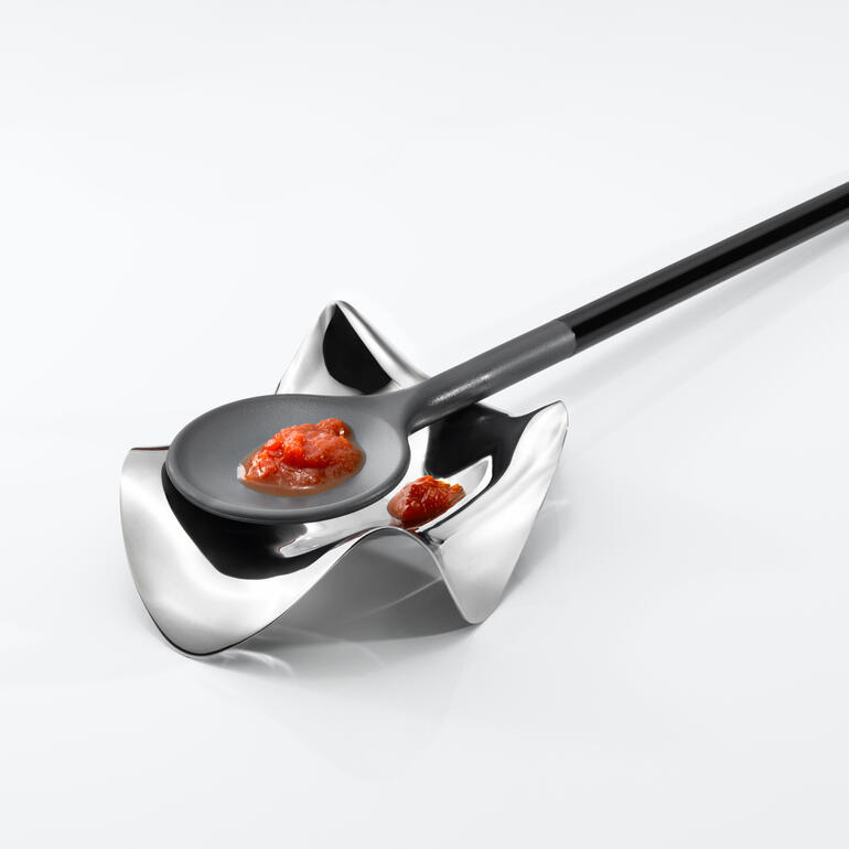 Moderne lepelhouder met een zwarte lepel en saus.