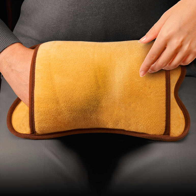 Elektronisch warmwaterkruik met een zachte, beige oppervlak in de hand.