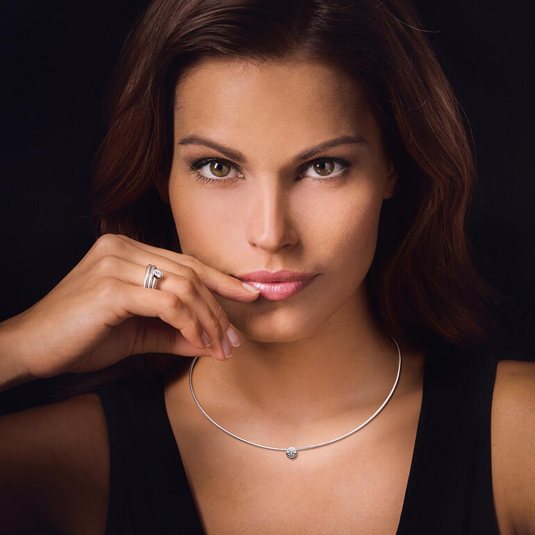 Vrouw draagt een briljant spiraalring en een kabelcollier.