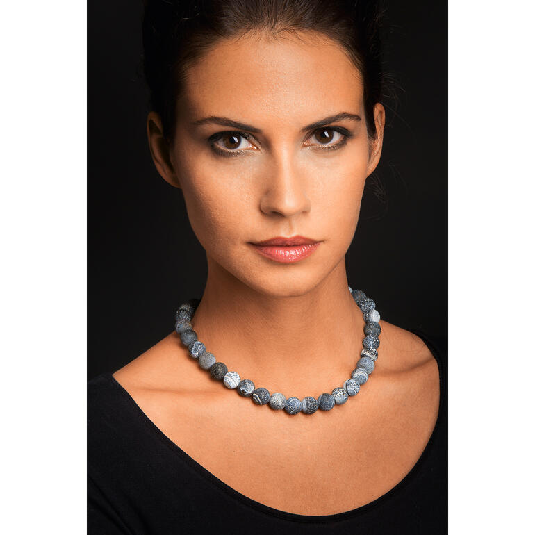 De grijsblauwe agaatstenen passen perfect bij sportieve en elegante kleding. Vrouw draagt agaat ketting met verschillende blauwe stenen
