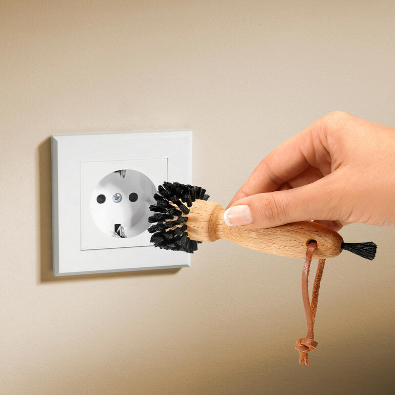Hand gebruikt een stopcontactborstel op een stopcontact