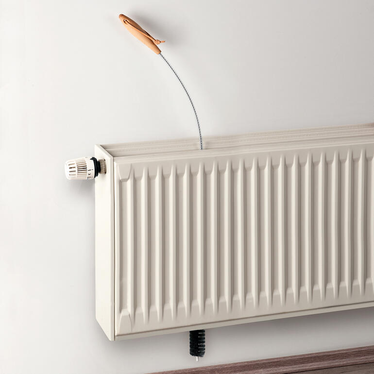 Zo werkt het: eenvoudig de radiatorborstel van boven in de smalle coulissen van de radiator steken. Radiatorborstel wordt op een radiator gebruikt.