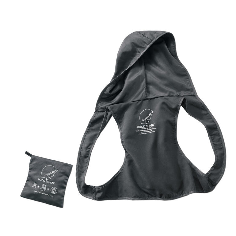 Hood To Go Hood To Go in gecomprimeerde staat naast een uitgespreide jas op een lichte achtergrond.