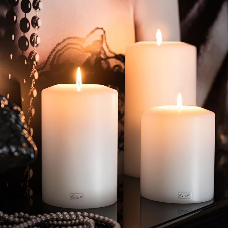 Drie witte duurzame kaarsen met brandende lont op een tafel