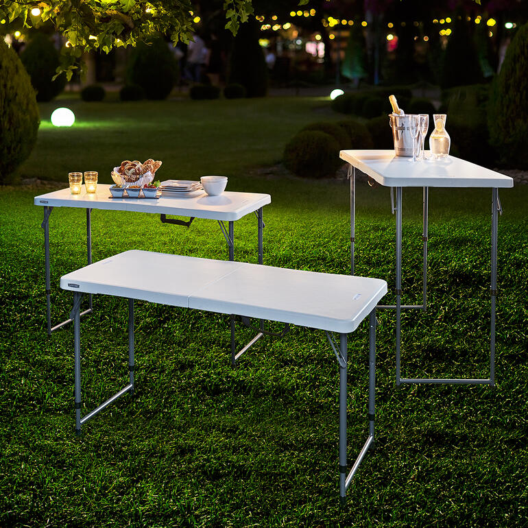 Vouwtafel, in hoogte verstelbaar Drie in hoogte verstelbare opvouwbare tafels buiten, klaar voor een picknick bij avondverlichting.