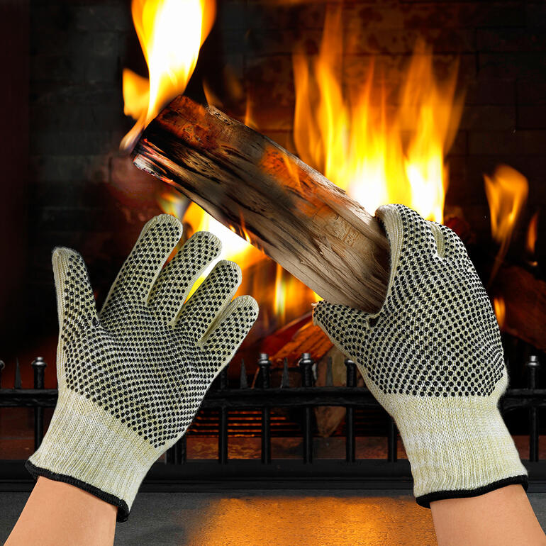 Hittebestendige handschoenen houden een stuk hout voor een vuur.