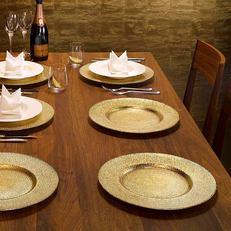 Set van 6 feestelijke glazen onderborden met gouden oppervlakte op een gedekte tafel.
