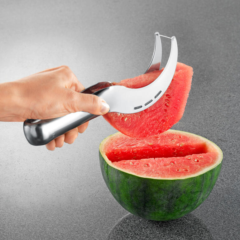 Meloensnijder Meloensnijder die een stuk uit een gehalveerde watermeloen tilt.