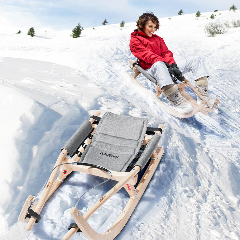 Kind rijdt met een houten slee in de sneeuw.