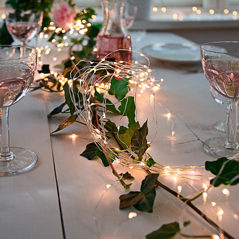 Engelshaarlichtsnoer op een tafel met glazen en bloemen gedecoreerd.