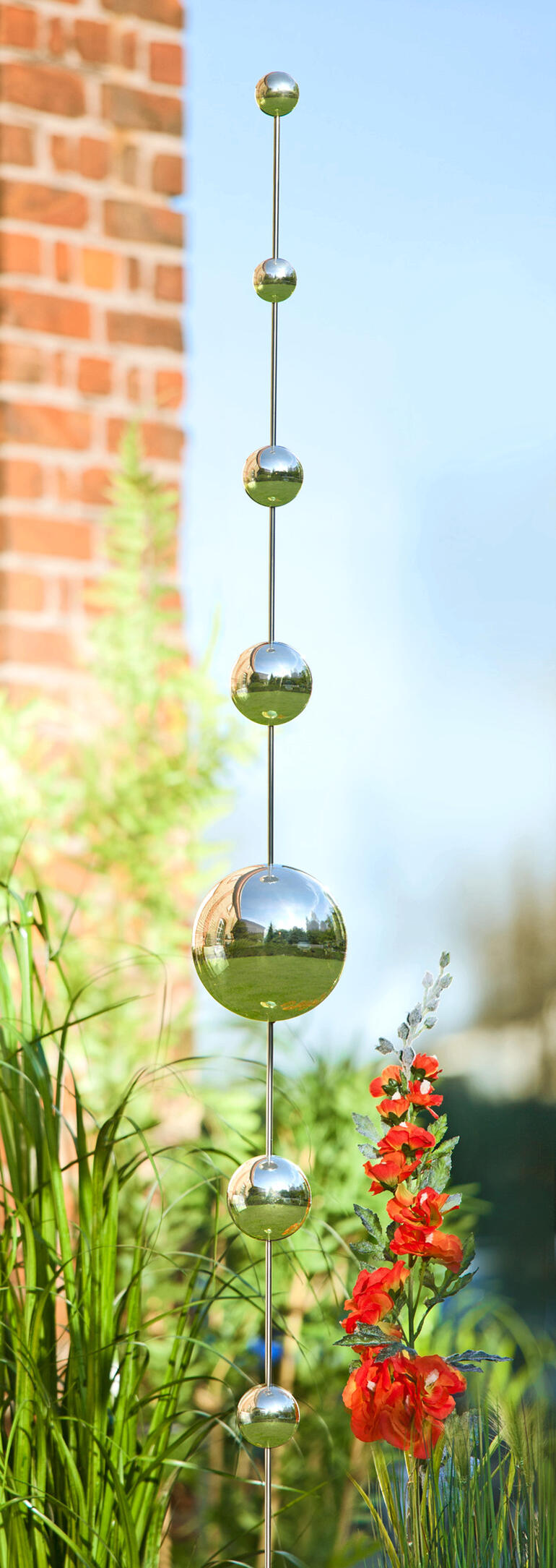 Metalen decoratie met bollen in verschillende maten, tussen groene planten