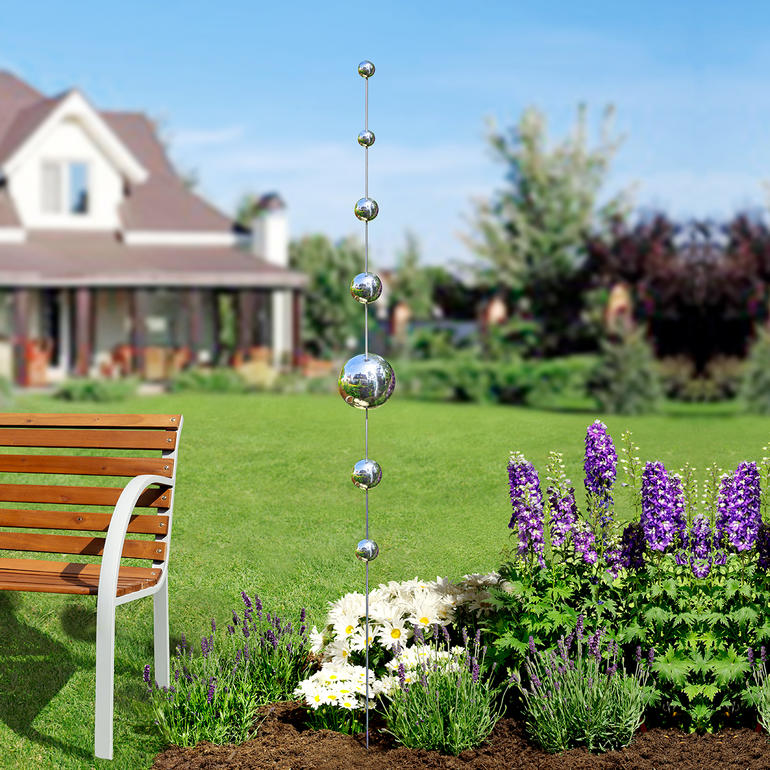 Tuin met bolvormige stokken tussen bloemen.